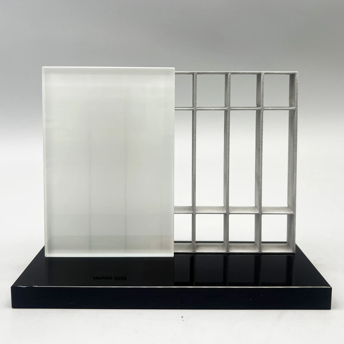 An architectural grid frame beside a clear dedication panel on a black base.