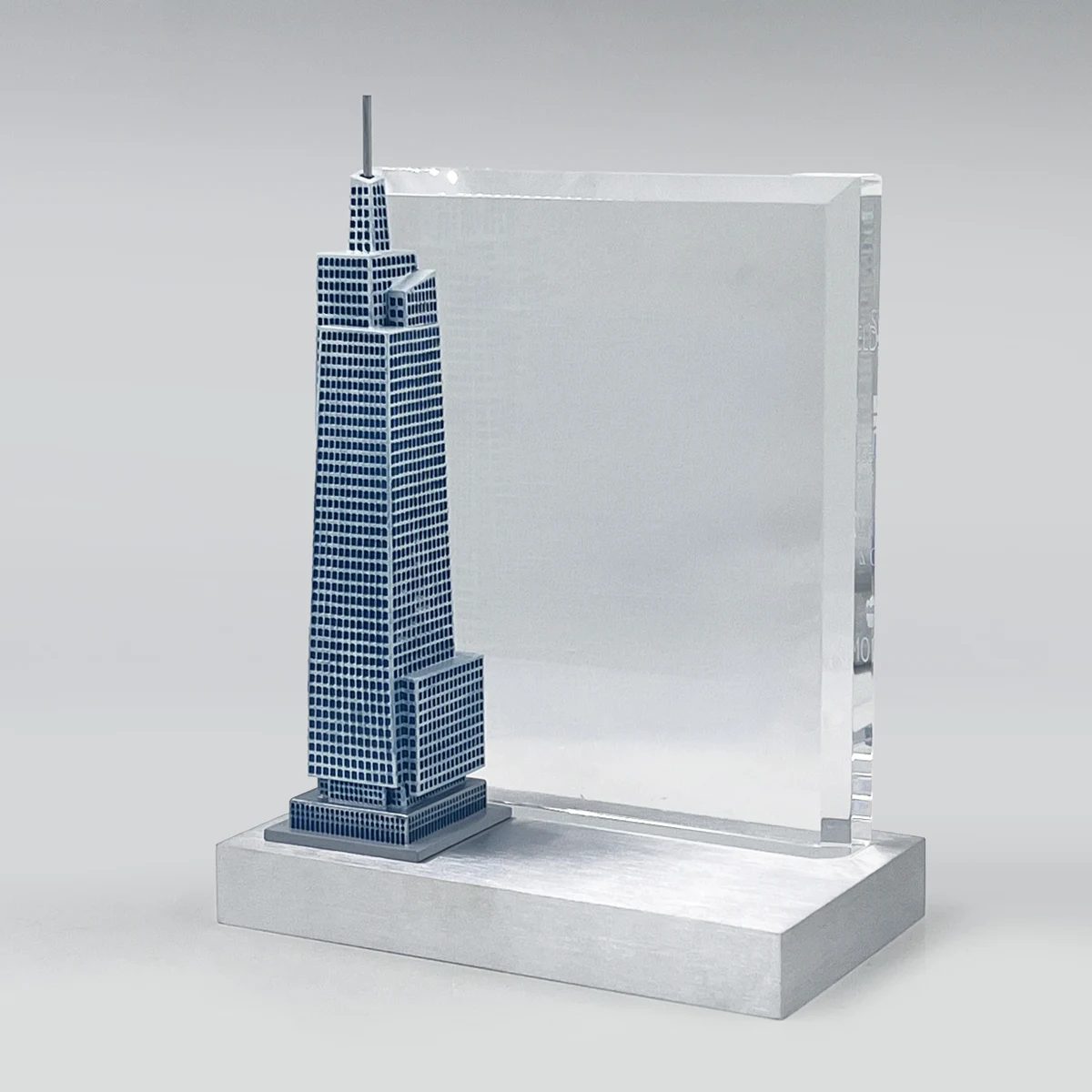 A slender blue skyscraper model paired with a clear dedication panel.